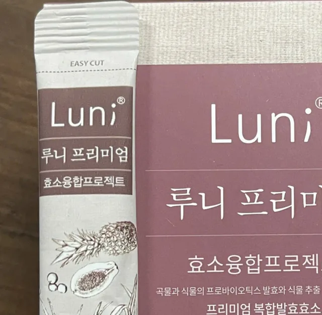 Cận cảnh một gói Luni Premium tựa vào cạnh hộp, đầu gói in dòng chữ EASY CUT và một đường xé chấm